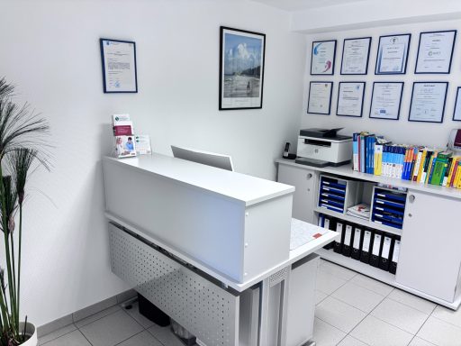 Moderne Empfangstheke in einem hellen Büro mit Urkunden und Drucker.
