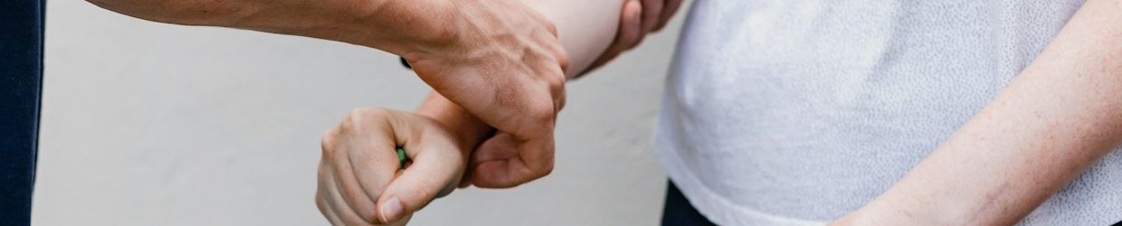 Eine Hand berührt sanft den Handgelenk einer anderen Hand während der Krankengymnastik.