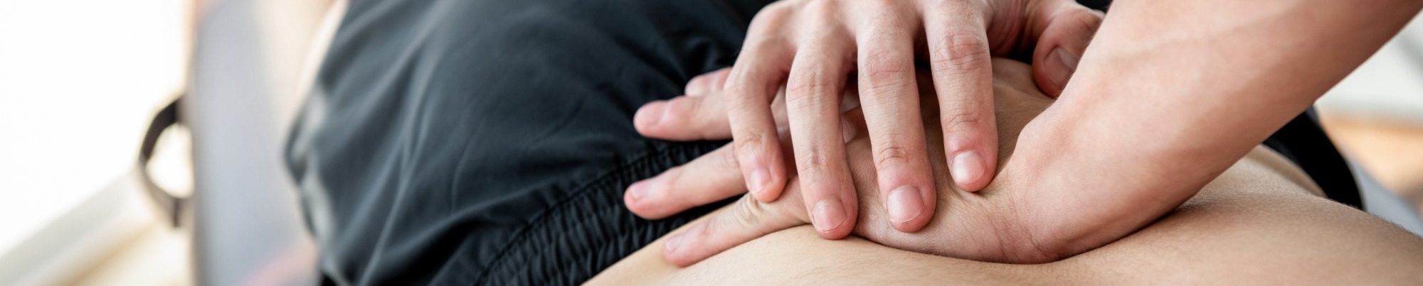 Manuelle Therapie Bergisch Gladbach Hände, die eine Mobilisation der Wirbelsäule durchführen, auf einem entspannten Patienten.